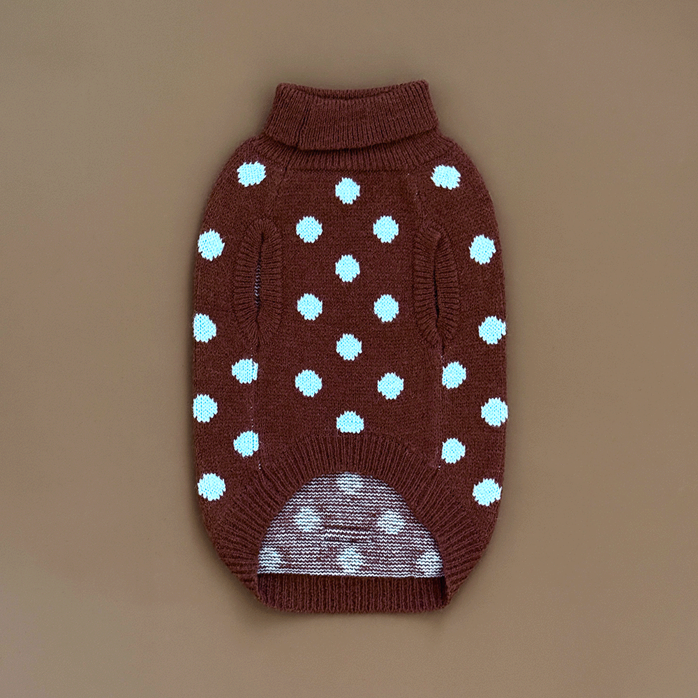 The reverse of a brown knit dog jumper with pale blue polka dots, on a solid beige background.