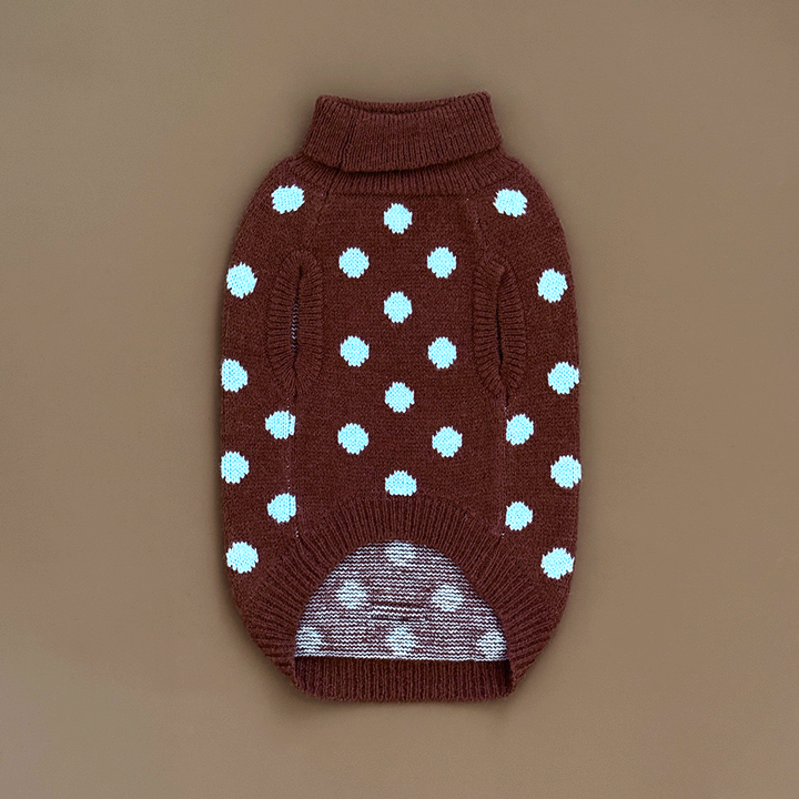 The reverse of a brown knit dog jumper with pale blue polka dots, on a solid beige background.