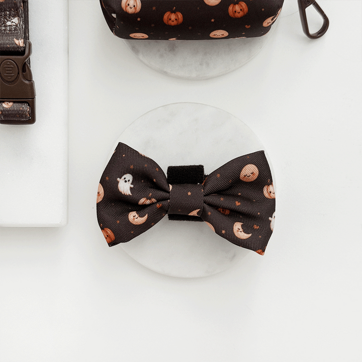 Brown dog bow tie with cute Halloween print featuring pumpkins, ghosts, and moons.