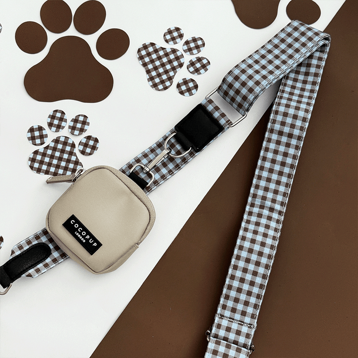 A brown and blue check print bag strap. with a beige treat pouch attached, for dog treats.