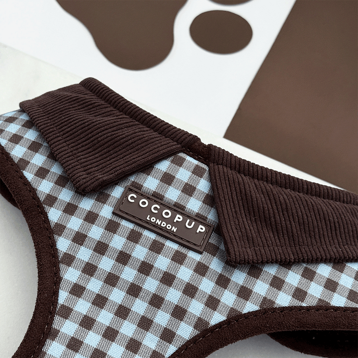 A brown and blue check print dog harness. With brown hardware and brown corduroy collar detail.