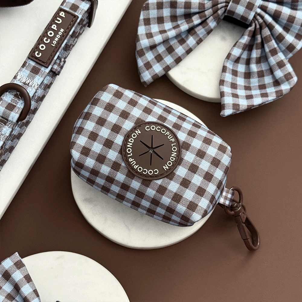 A brown and blue check print poop bag holder, to hold dog poo bags. With brown hardware.