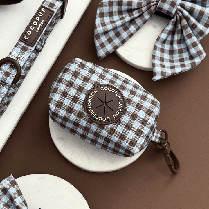 A brown and blue check print poop bag holder, to hold dog poo bags. With brown hardware.