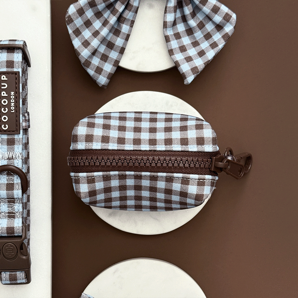 A brown and blue check print poop bag holder, to hold dog poo bags. With brown hardware.