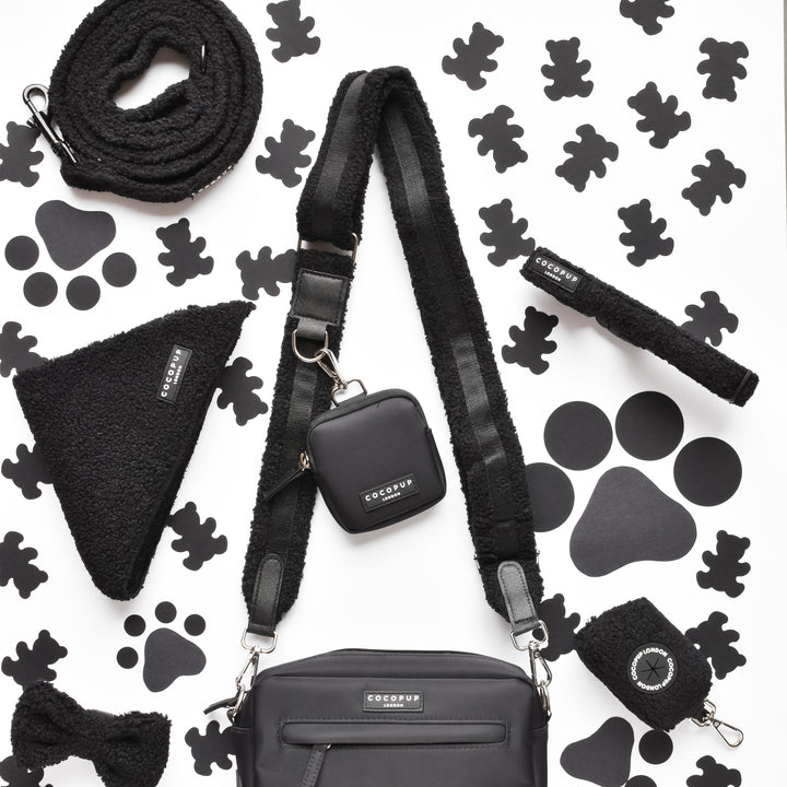 Cocopup London's Teddy Bag Strap - Baloo pet accessory set is displayed on a white background with black bear-shaped patterns. The set includes a fluffy design leash, harness, small Cocopup Dog Walking Bag, bow tie, bandana, and keychain—all featuring matching fuzzy textures and branded tags.