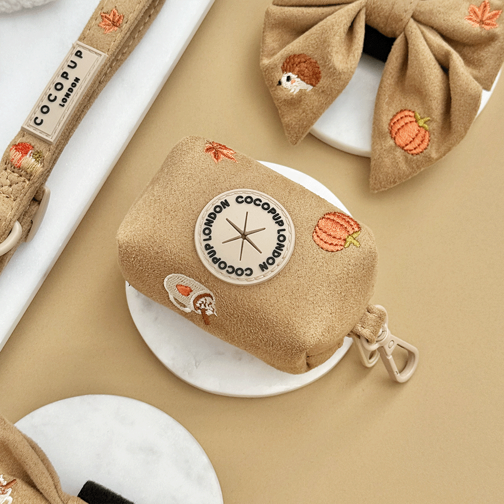 Brown poop bag dispenser, for dog poo bags, with autumnal-themed embroidery of pumpkins, leaves, a coffee cup, and mushrooms.
